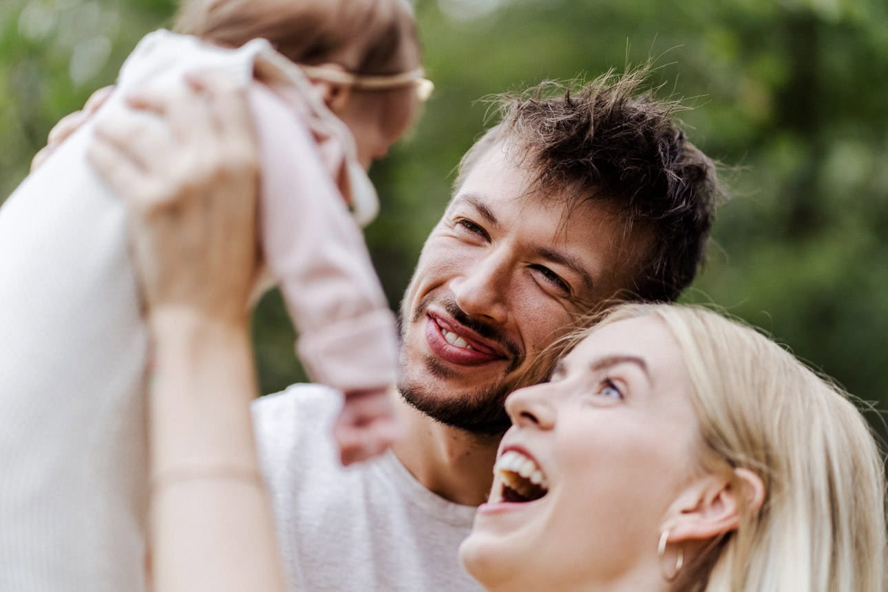 Lächelnde Eltern halten ein Baby und genießen einen lustigen Moment zusammen.
