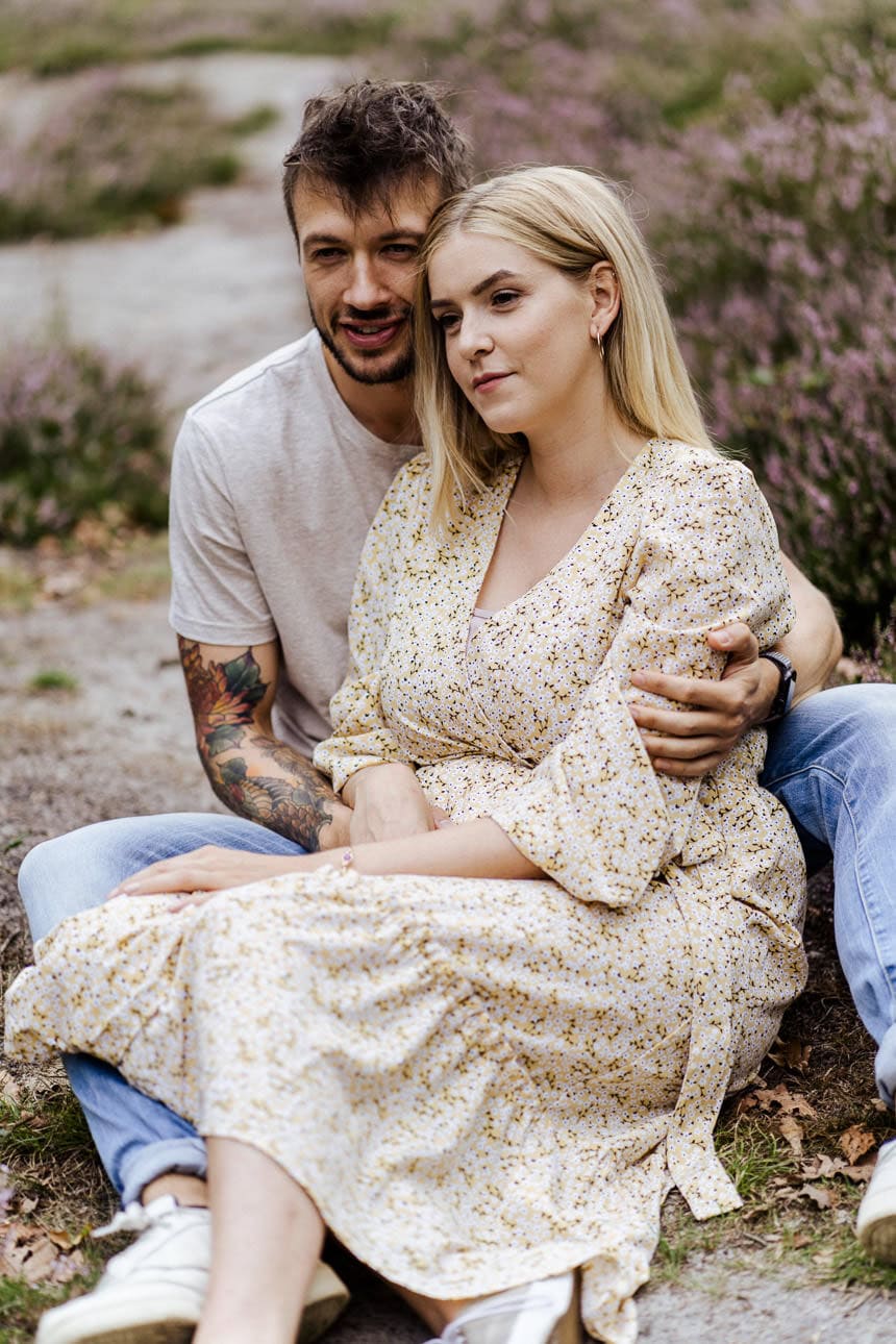 Ein Paar sitzt entspannt auf einem Pfad in der Heide, genießt die Natur und die gemeinsame Zeit.