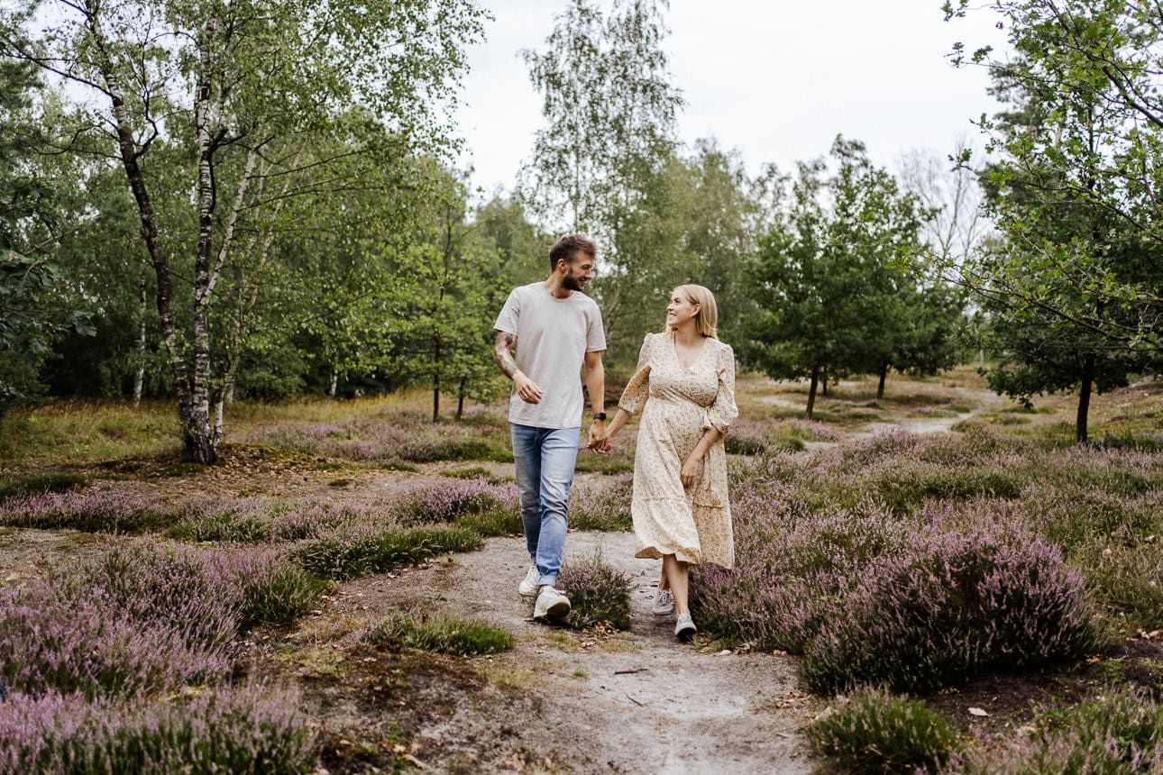 Ein verliebtes Paar genießt einen romantischen Spaziergang in der Heide, umgeben von der Schönheit der Natur.