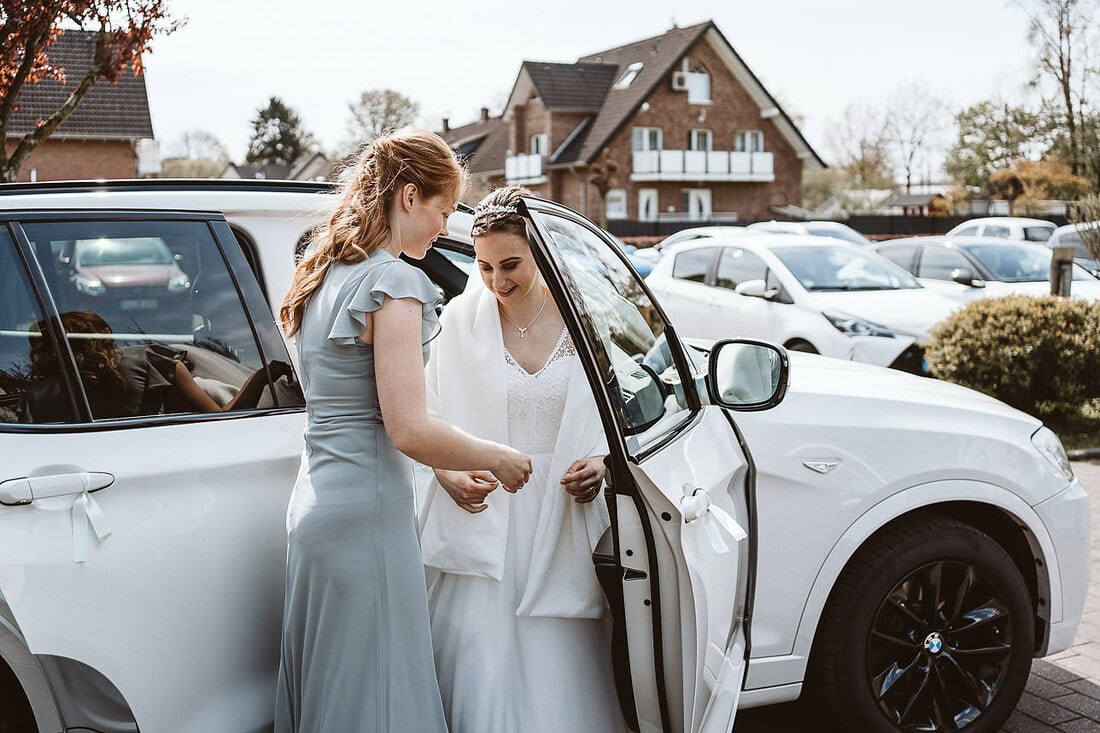 Die Braut und ihre Brautjungfer steigen aus dem Auto, auf dem Weg zur Hochzeit, voller Vorfreude und Aufregung.