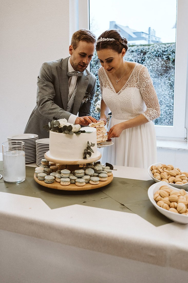 Ein Brautpaar nimmt sich ein Stück von ihrer Hochzeitstorte.