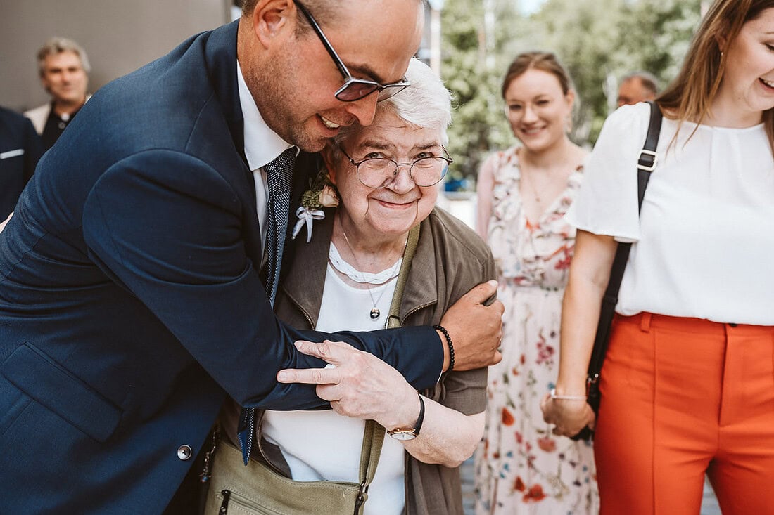 Gäste gratulieren und umarmen einen Bräutigam.