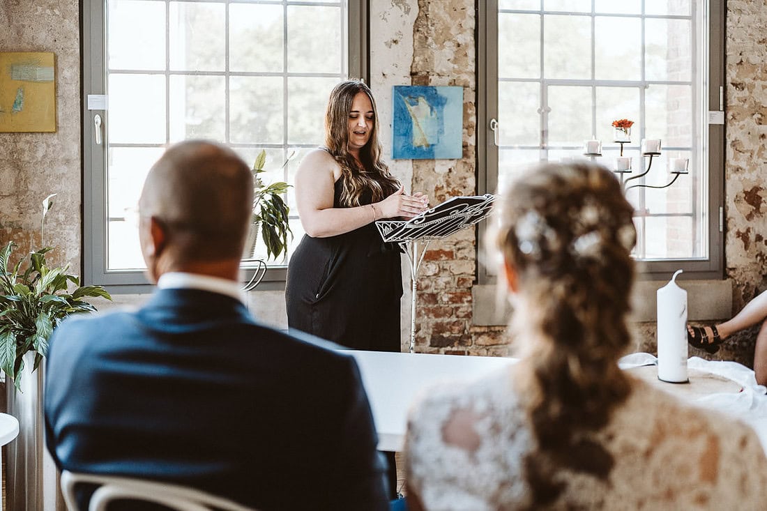 Eine Traurednerin hält eine emotionale Traurede für das Hochzeitspaar.