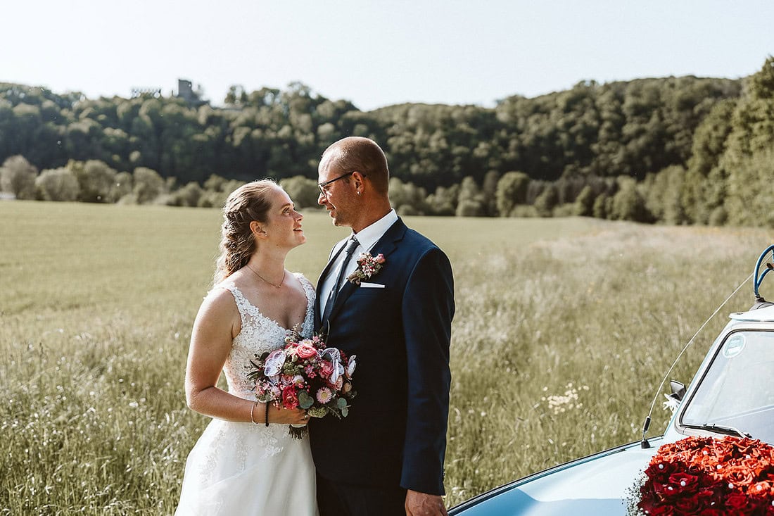 Ein Hochzeitspaar schaut sich an. Im Hintergrund ist die Burgruine in Windeck zu erkennen.