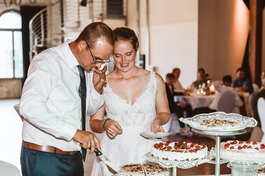 Braut und Bräutigam schneiden die Hochzeitstorte an.