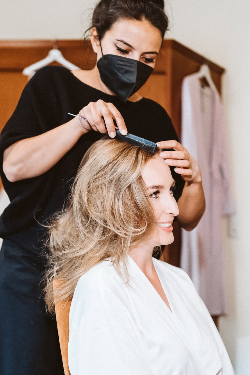 Eine Braut bekommt beim Getting Ready von einer Stylistin die Haare gemacht.