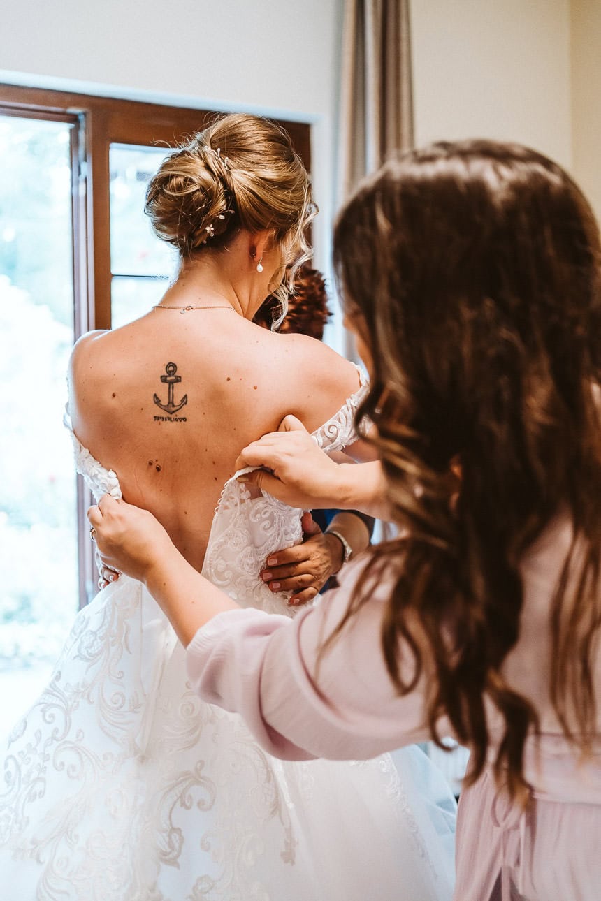 Eine Braut zieht ihr Kleid an und bekommt Hilfe von ihrer Trauzeugin.