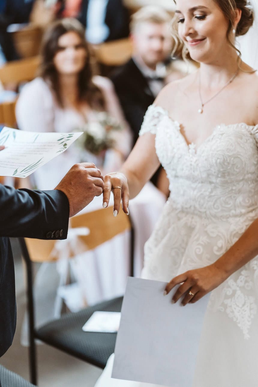 Ein Bräutigam liest sein Eheversprechen und steckt seiner Braut den Ehering an den Finger.