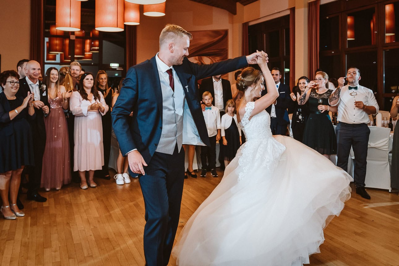 Ein Hochzeitspaar tanzt den ersten Tanz und die Hochzeitsgäste stehen um die Beiden herum.