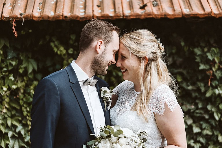 Ein Hochzeitspaar steht Stirn an Stirn auf einem Bauernhof in Bad Laer und schaut sich tief in die Augen.