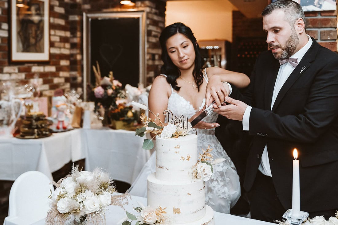 Ein Hochzeitspaar schneidet eine Hochzeitstorte an.