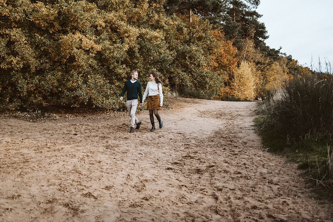 Ein verliebtes Paar läuft Hand in Hand über einen sandigen Weg.